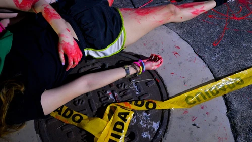 Women lay on the ground during a protest with fake blood on body